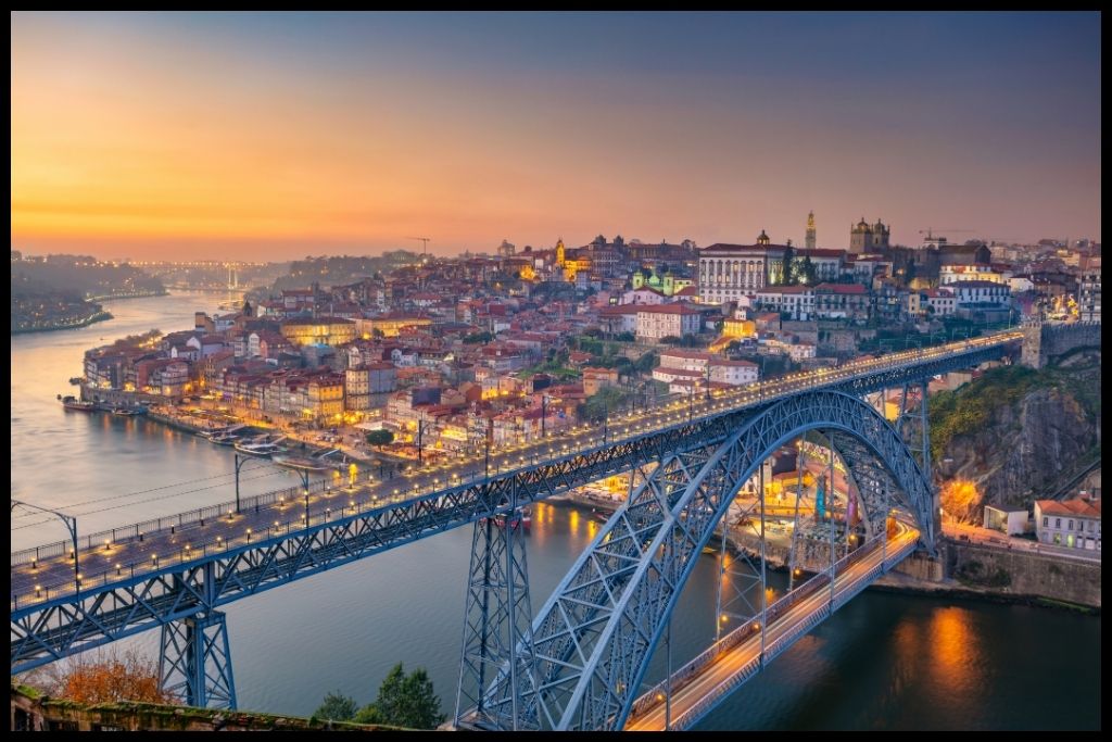 View of Porto from above showing the Douro River and red-tiled rooftops at sunset