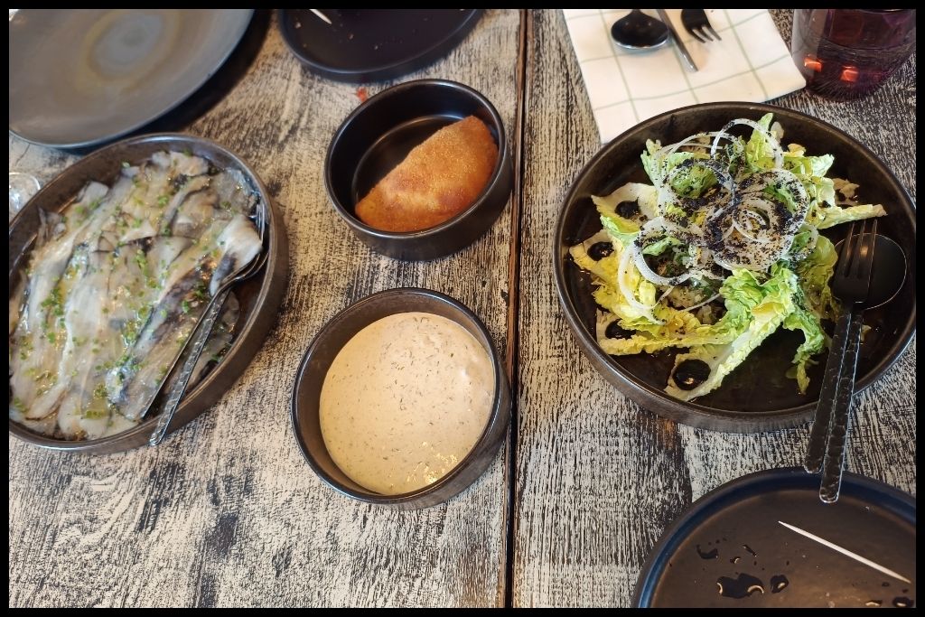 Where to Eat Bacalhau in Porto: here you have some starters left laminated smoked cod, center a Spanish style cod-fish rissole with fennel mayo and right the octopus salad with green sauce.